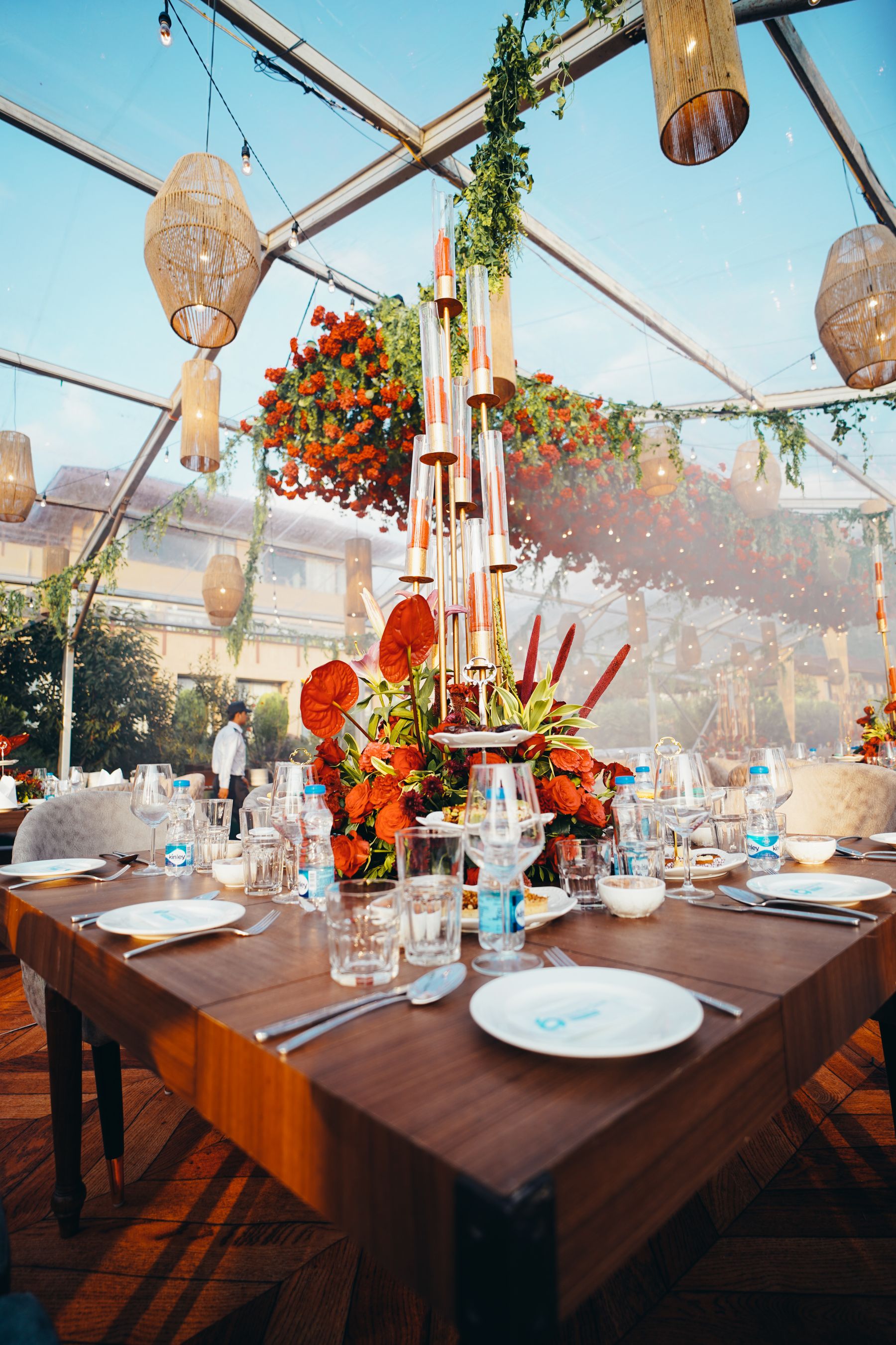 Flowers and candlelight on a reception table beneath a clear tent